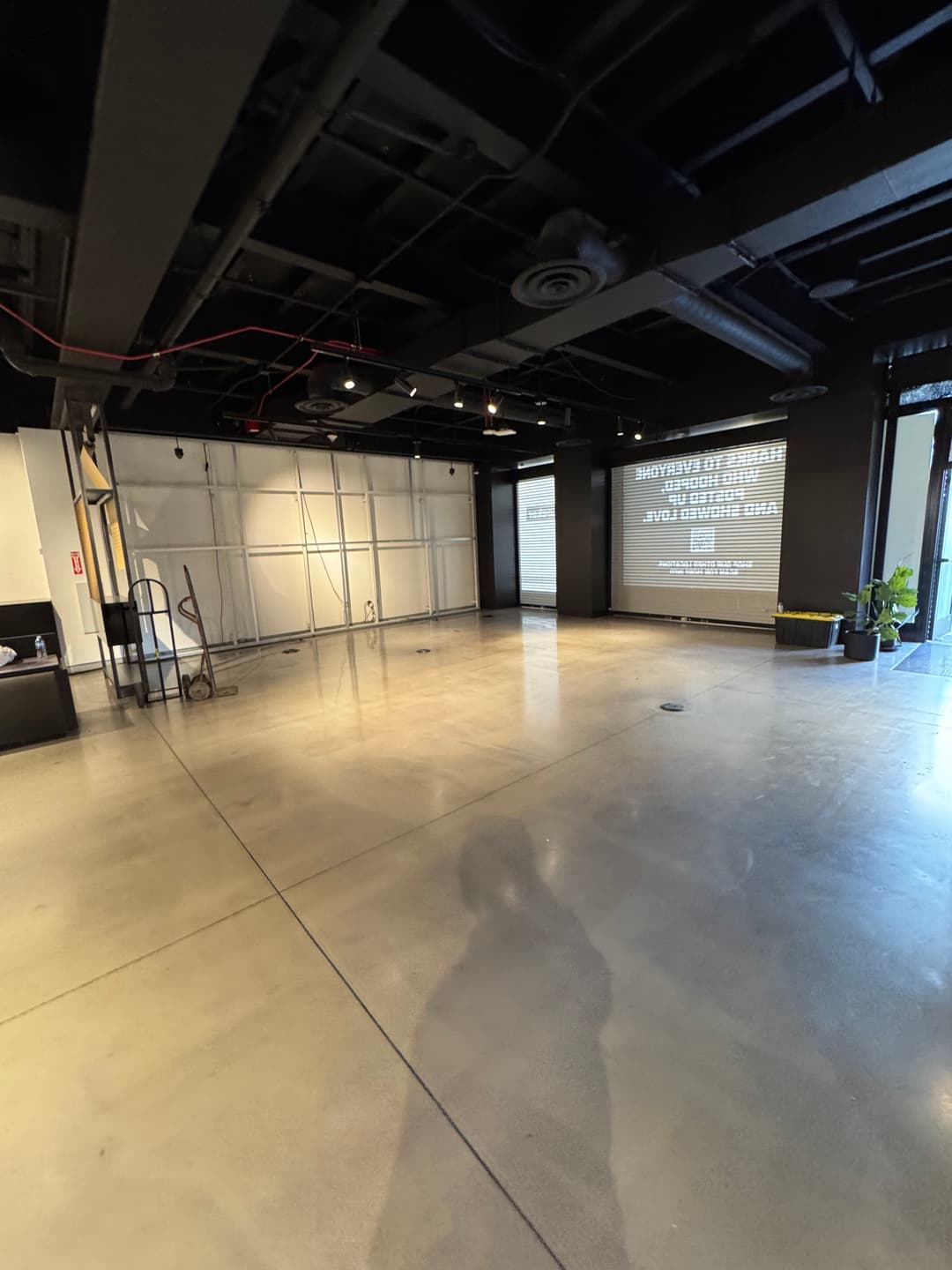 Spacious commercial space with polished concrete floor and large projection screen.