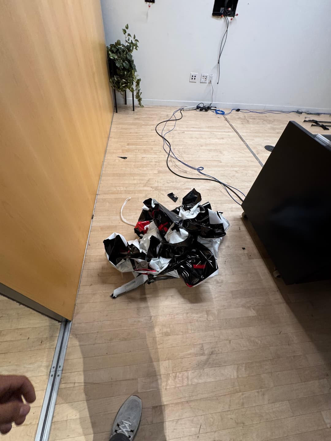 Messy office floor with crumpled black and red fabric, wires, and minimal decor.