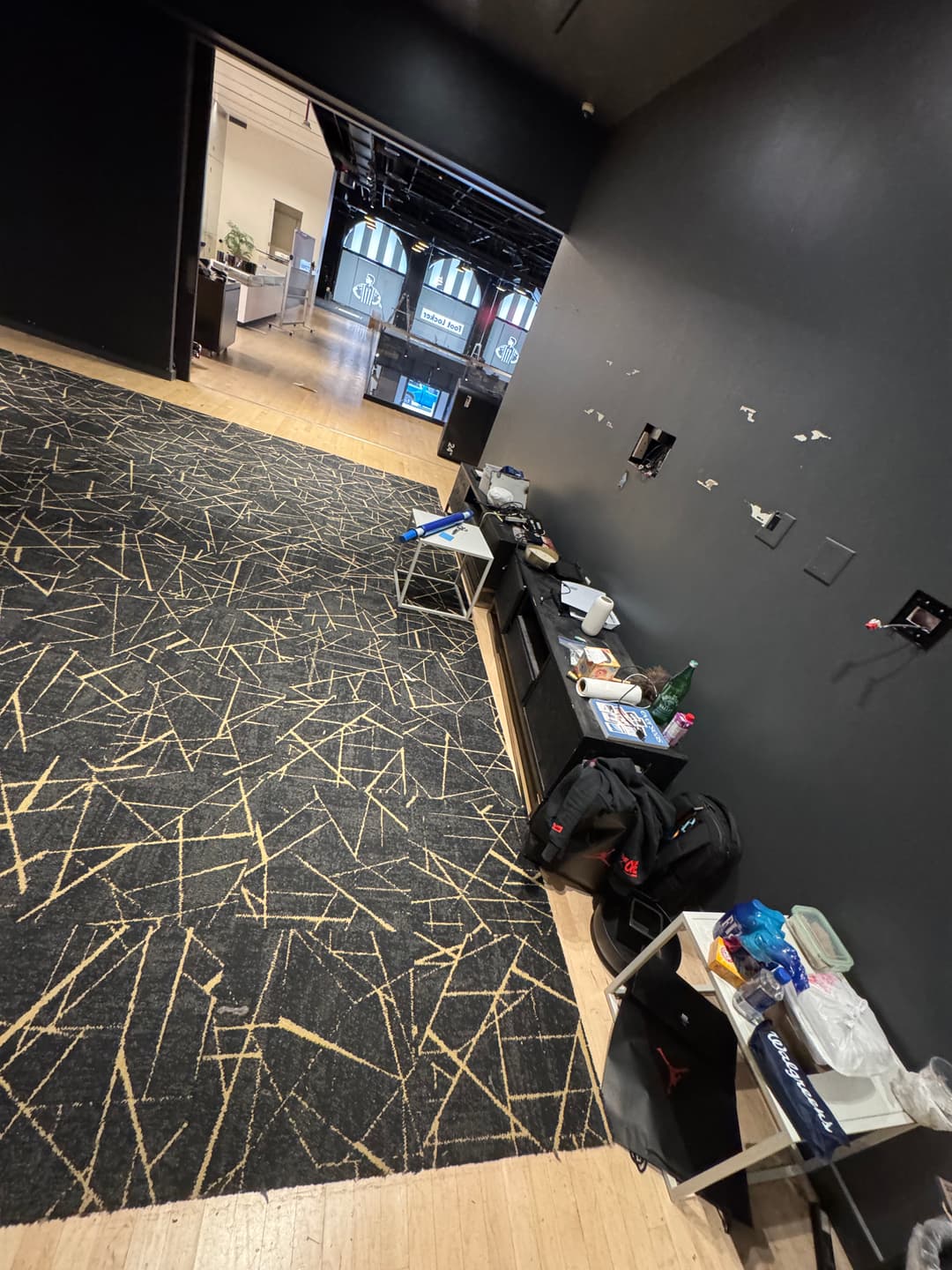 Empty room with a patterned carpet, unorganized equipment, and an entrance to another space.