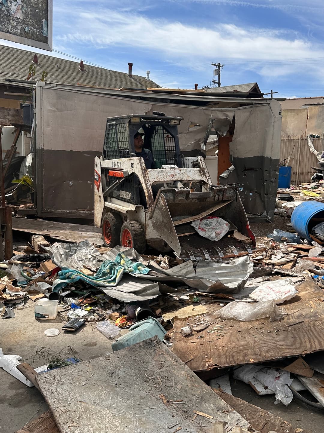 Bobcat clearing debris in a cluttered construction site, showcasing cleanup efforts.