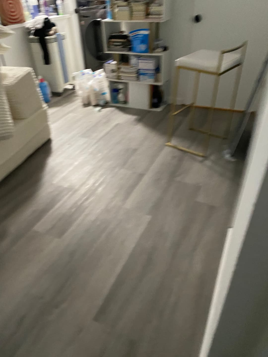 Cozy room interior with light wood flooring, storage shelves, and a gold bar stool.