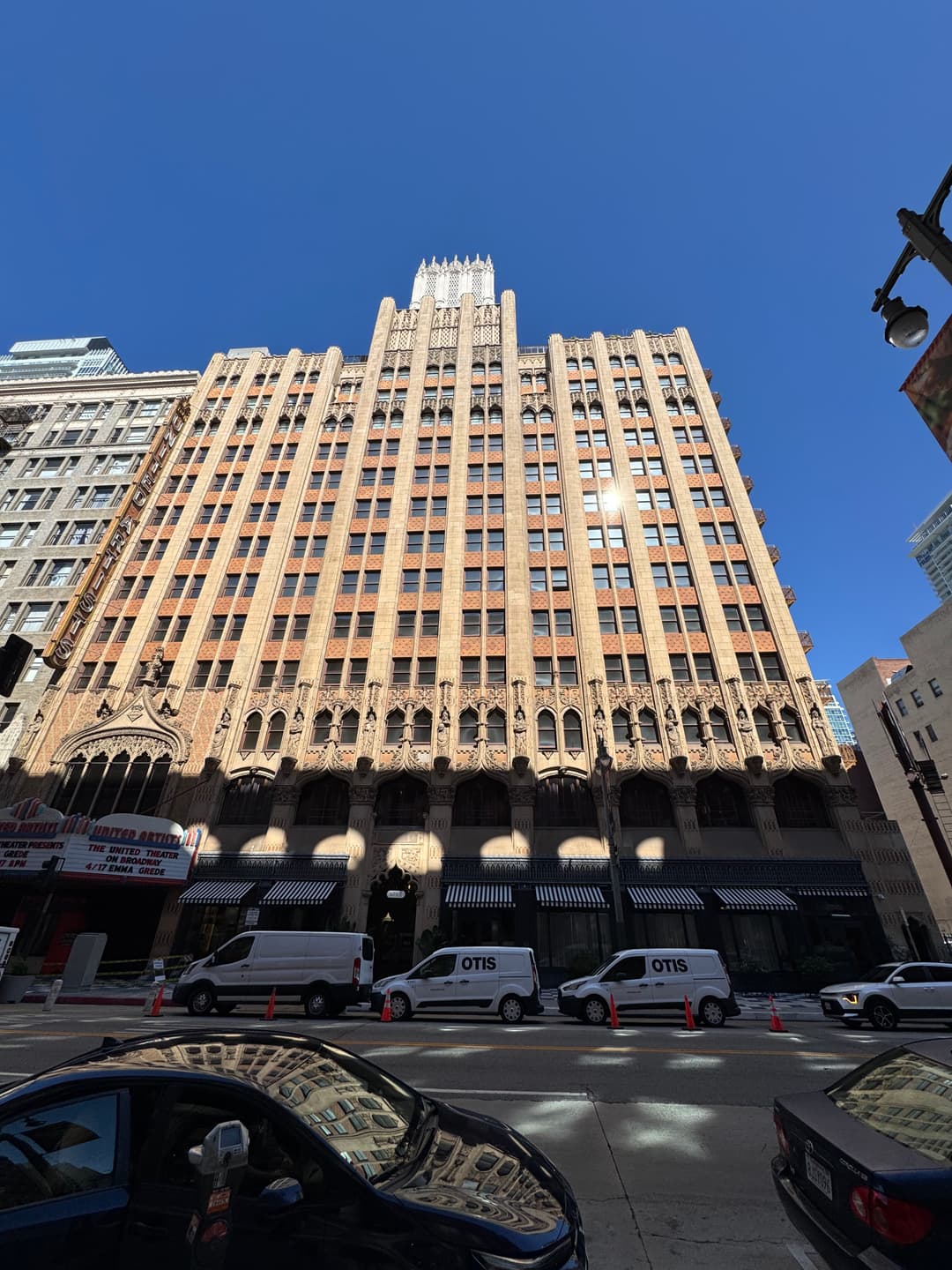 Historic art deco building with intricate details and a clear blue sky backdrop, urban street scene.