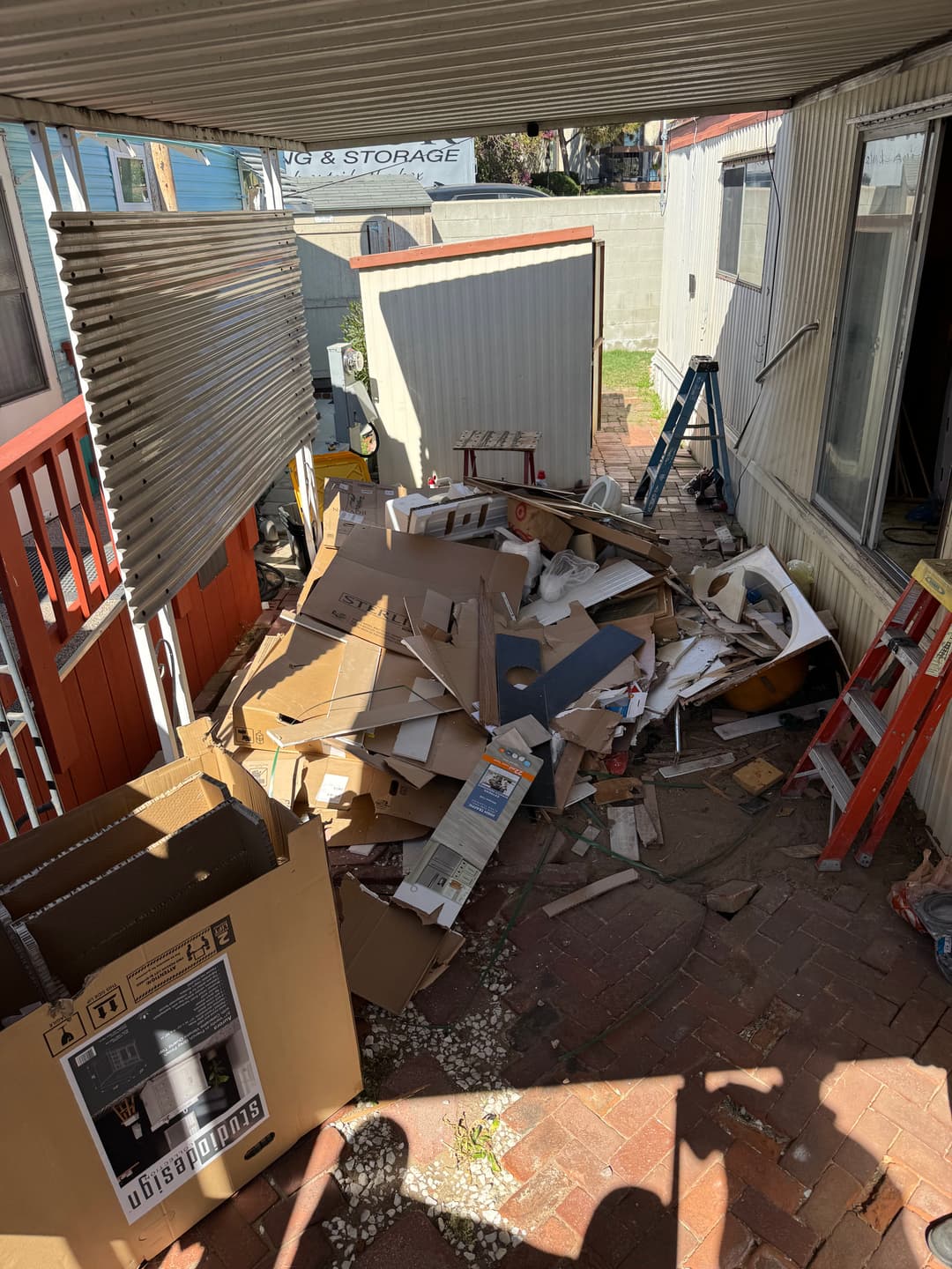 Cluttered outdoor area filled with piles of cardboard and debris near a trailer.