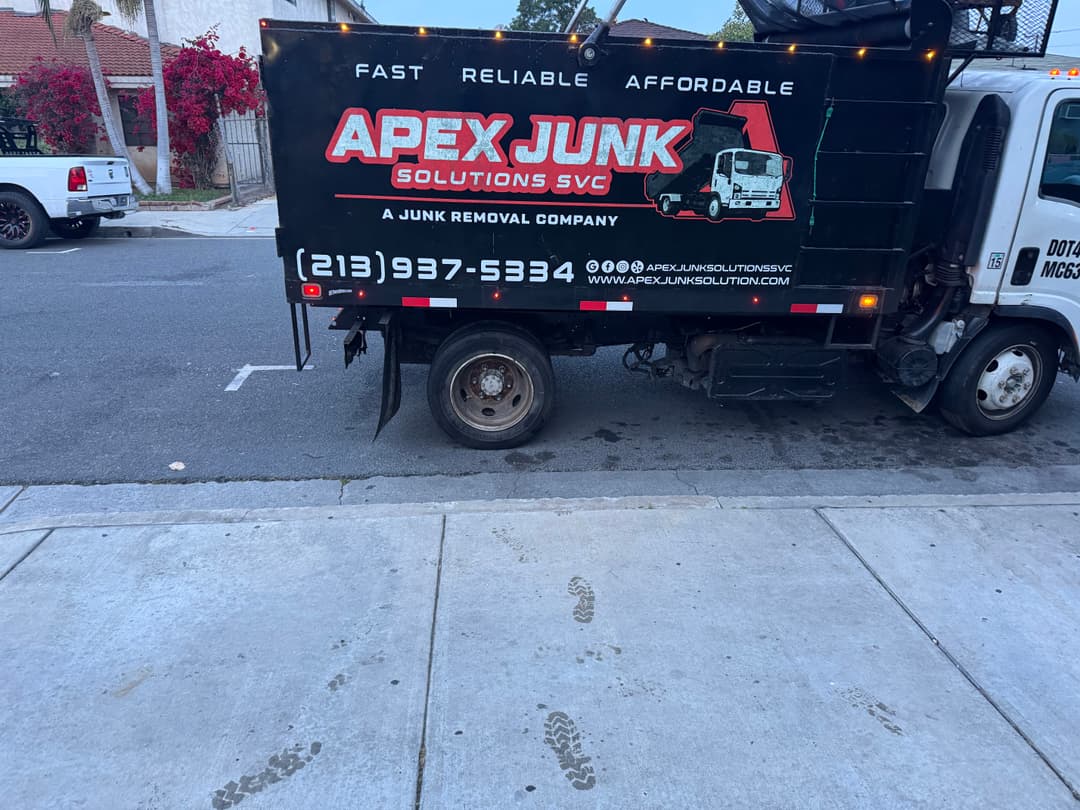 Apex Junk Solutions truck parked, showcasing branding and contact information on the side.