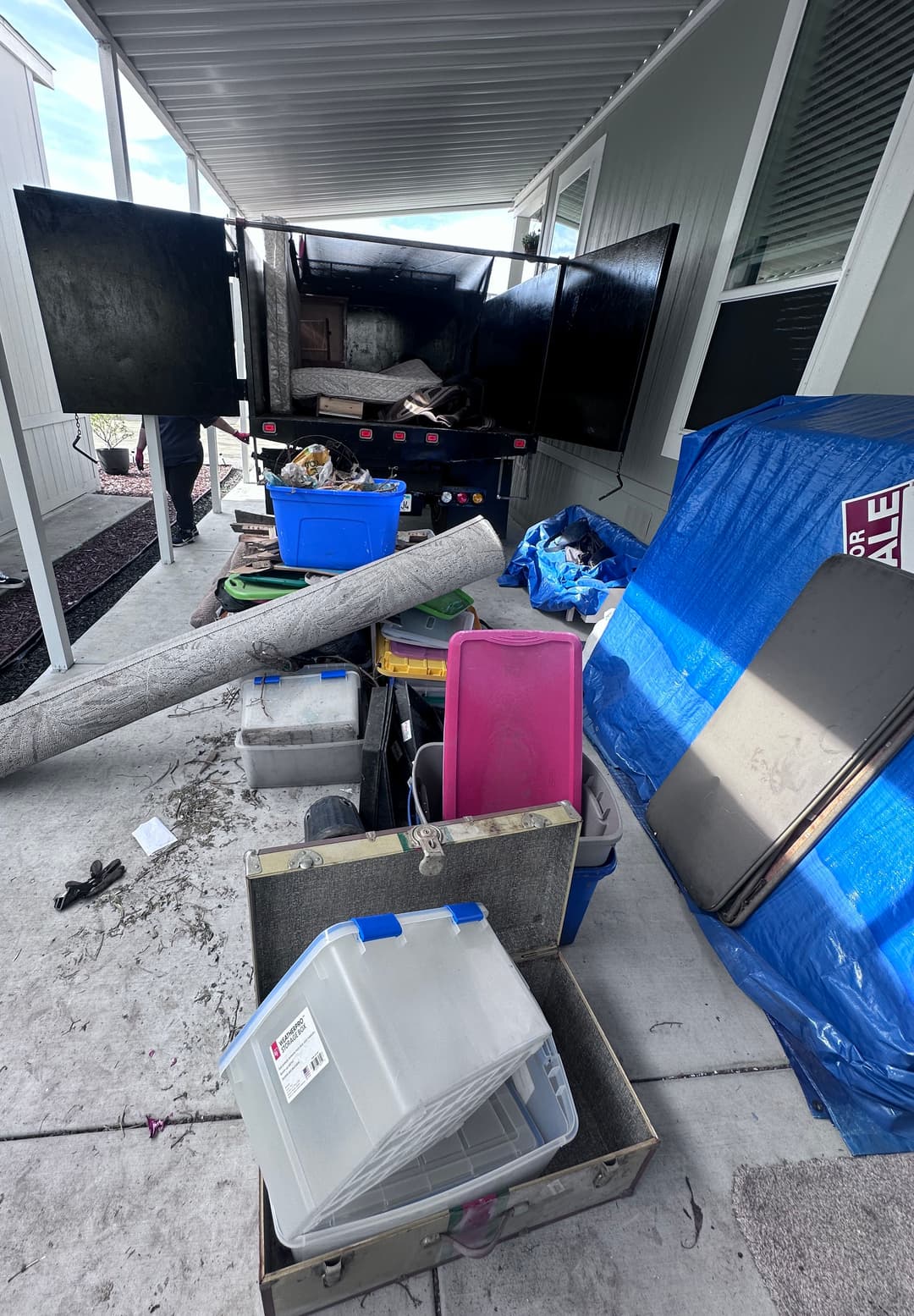 Cluttered outdoor area with boxes, containers, and a truck parked nearby.