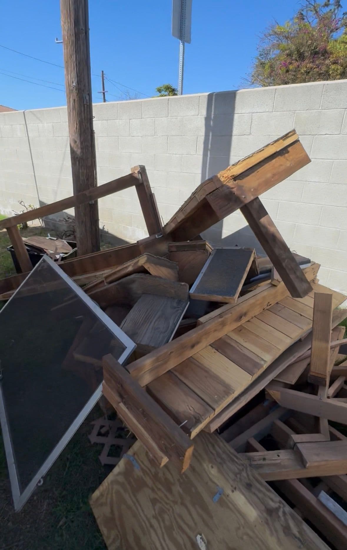 Piled wooden furniture debris against a wall, showcasing discarded items and recycling needs.